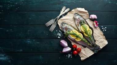 Siyah ahşap arka planda sebze li çiğ balık. Balık alabalığı. Üst te. Metniniz için boş alan.