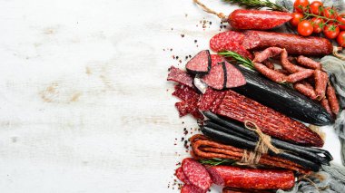 Beyaz ahşap arka planda kurutulmuş salam ve füme sosis çeşitleri. Üst Manzara. Metnin için boş yer.