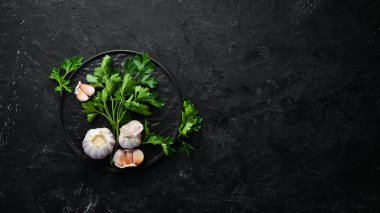 Koyu arkaplanda taze maydanoz ve sarımsak. Sebzeler. Üst Manzara. Metnin için boş yer.