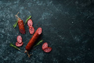 Traditional smoked salami sausage with spices. Slice sausages. Rosemary. Top view. Free space for your text.