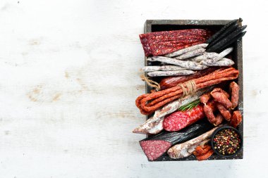 Salami, sausages, spices and meat products in a wooden box. Top view. Free space for your text.