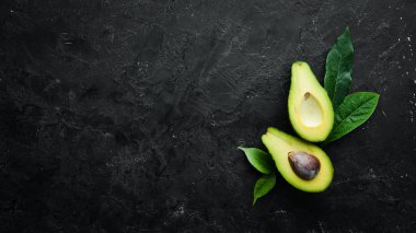 Fresh avocado on black stone background. Citrus fruits. Top view. Free space for your text.