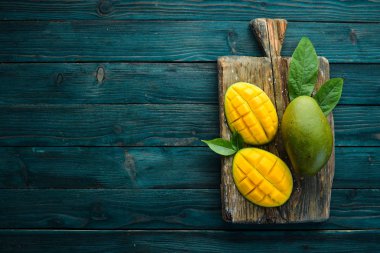 Mavi ahşap arka planda mango meyvesi. Tropik meyveler. Üst Manzara. Metnin için boş yer.