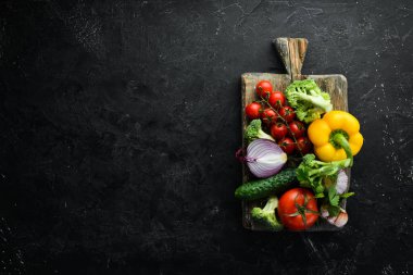 Tahta kutuda taze sebzeler, siyah taş arka planda. Tropik meyveler. Üst Manzara. Metnin için boş yer.