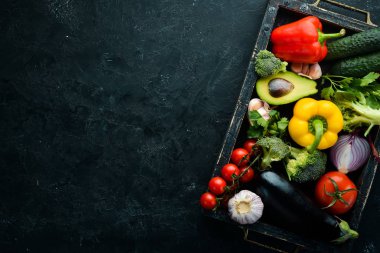 Tahta kutuda taze sebzeler, siyah taş arka planda. Tropik meyveler. Üst Manzara. Metnin için boş yer.