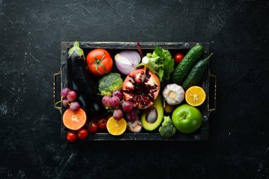 Sebze, meyve, sağlıklı yiyecekler. Siyah taş arka planda meyveler ve sebzeler. Tropik meyveler. Üst Manzara. Metnin için boş yer.