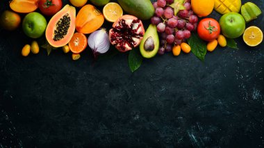 Sebze, meyve, sağlıklı yiyecekler. Siyah taş arka planda meyveler ve sebzeler. Tropik meyveler. Üst Manzara. Metnin için boş yer.