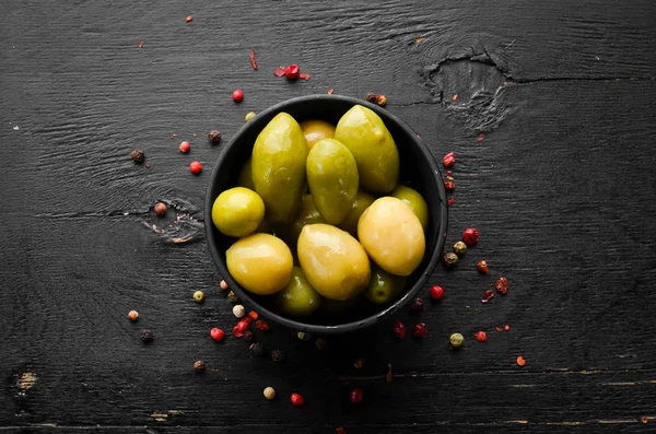 Pickled olives in a black bowl. Top view. Free space for your text.