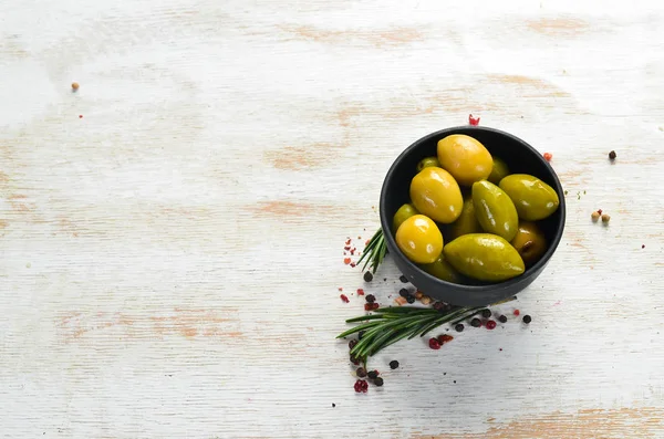 Pickled olives in a black bowl. Top view. Free space for your text.