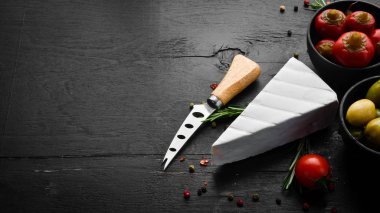 Brie cheese on black background. Top view. Free space for your text.