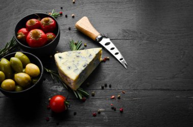 Blue cheese with mold on black background. Top view. Free space for your text.