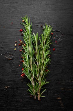Spices and herbs. Fresh rosemary on black wooden background. Top view. Free space for your text.