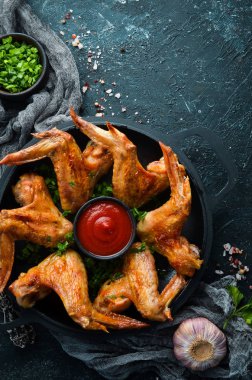 Baked chicken wings in a pan with ketchup and onions. Barbecue. Top view. Free space for your text. clipart