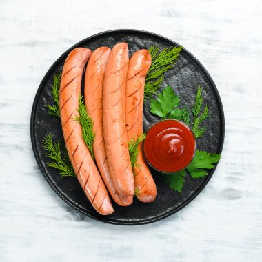 Siyah tabakta kaynamış sosis ve ketçap. Üst Manzara. Metnin için boş yer.