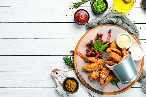 Snacks to beer on the board. Chicken wings, nuggets, sausages. Top view. Free space for your text.