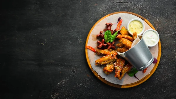 Snacks to beer on the board. Chicken wings, nuggets, sausages. Top view. Free space for your text.