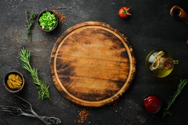 Kitchen board and vegetables with spices on black stone background. Top view. Free space for your text.