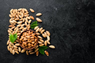 Almond nut in a bowl. Nuts on a black stone background. Top view. Free space for your text.