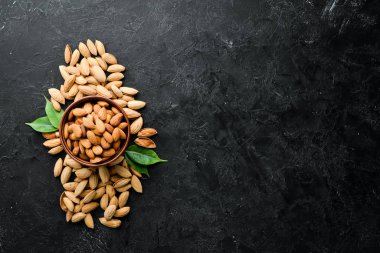 Almond nut in a bowl. Nuts on a black stone background. Top view. Free space for your text.