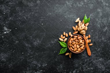 Almond nut in a bowl. Nuts on a black stone background. Top view. Free space for your text.