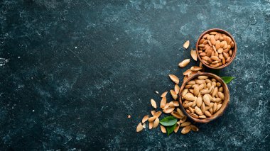 Almond nut in a bowl. Nuts on a black stone background. Top view. Free space for your text.
