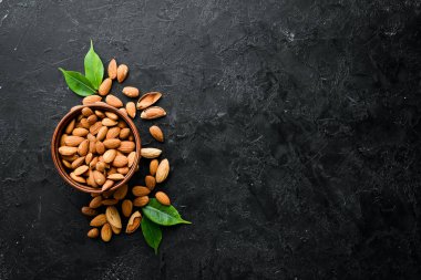 Almond nut in a bowl. Nuts on a black stone background. Top view. Free space for your text.