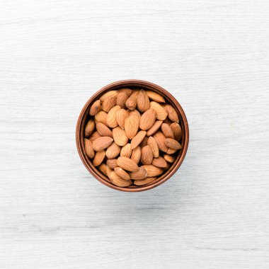Almonds in bowl on white wooden table. Top view. Free space for your text.