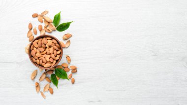 Almonds in bowl on white wooden table. Top view. Free space for your text.