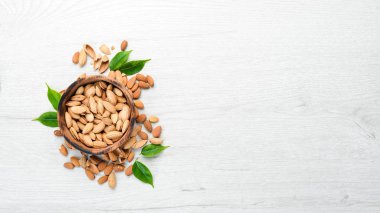 Almonds in bowl on white wooden table. Top view. Free space for your text.