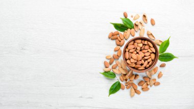 Almonds in bowl on white wooden table. Top view. Free space for your text.