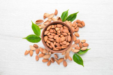 Almonds in bowl on white wooden table. Top view. Free space for your text.