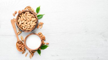 Badem sütü ve badem beyaz ahşap bir masada. Üst Manzara. Metnin için boş yer.