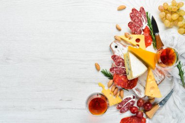 İtalyan antipasti şarap aperatifleri. Beyaz ahşap arka planda peynir, salam ve üzüm çeşitleri. İtalyan mutfağı. Üst Manzara. Metnin için boş yer.