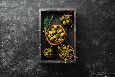 Kapari. Siyah taşlı arka planda bir kasede marine edilmiş kapari. Üst Manzara. Metnin için boş yer.