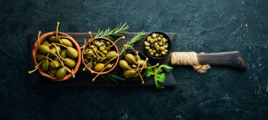 Kapari. Siyah taşlı arka planda bir kasede marine edilmiş kapari. Üst Manzara. Metnin için boş yer.