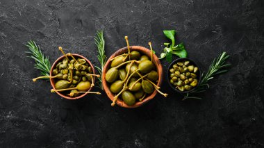 Kapari. Siyah taşlı arka planda bir kasede marine edilmiş kapari. Üst Manzara. Metnin için boş yer.