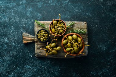 Kapari. Siyah taşlı arka planda bir kasede marine edilmiş kapari. Üst Manzara. Metnin için boş yer.