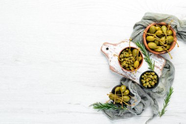 Beyaz ahşap arka planda bir kasede marine edilmiş kapari. Üst Manzara. Metnin için boş yer.