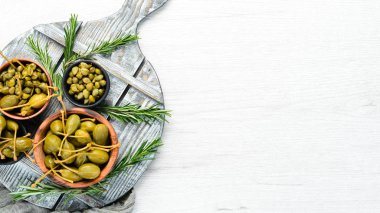 Beyaz ahşap arka planda bir kasede marine edilmiş kapari. Üst Manzara. Metnin için boş yer.