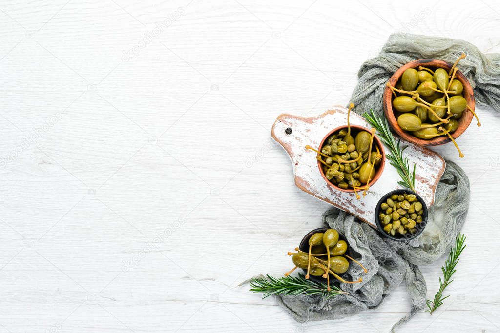 Marinated capers in a bowl on a white wooden background. Top view. Free space for your text.