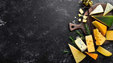 Peynir. Siyah taş arka planda peynir ve abur cubur çeşitleri. Üst Manzara. Metnin için boş yer.
