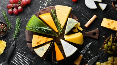 Peynir. Siyah taş arka planda peynir ve abur cubur çeşitleri. Üst Manzara. Metnin için boş yer.