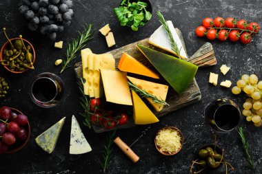 Siyah taş arka planda şarap, peynir ve atıştırmalıklar. Çeşit çeşit peynir. Üst Manzara. Metnin için boş yer.