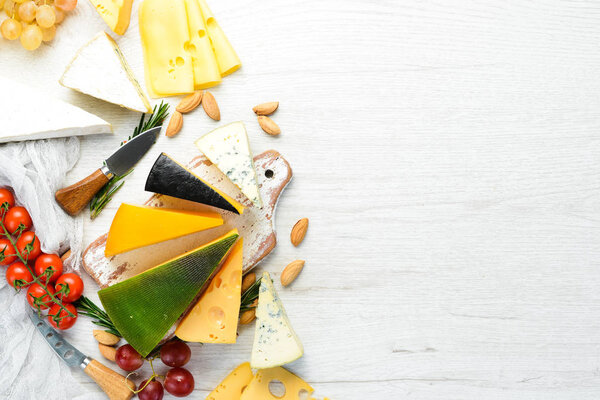 Assorted cheese and snacks on white wooden background. Dairy products. Top view. Free space for your text.