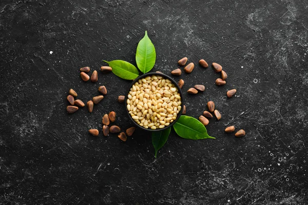 Pine nuts on a black stone background. Superfood. free space for your text. Top view.