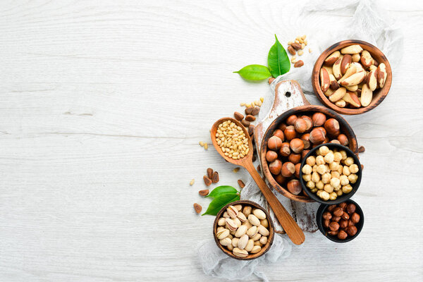 Assortment of nuts in bowls on white wooden background. free space for your text. Top view.