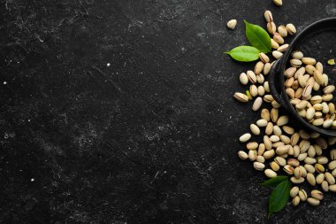 Siyah taşlı arka planda tuzlu şam fıstığı. Metnin için boş yer. Üst görünüm.