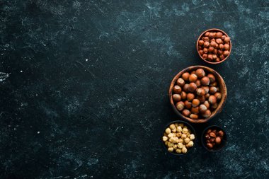 Siyah taşlı arka planda bir kasede fındık. Çatlak. Metnin için boş yer. Üst görünüm.