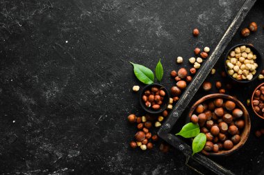 Siyah taşlı arka planda bir kasede fındık. Çatlak. Metnin için boş yer. Üst görünüm.