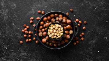 Siyah taşlı arka planda bir kasede fındık. Çatlak. Metnin için boş yer. Üst görünüm.